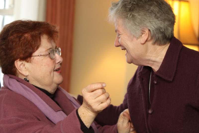 two women laughing and holding hands