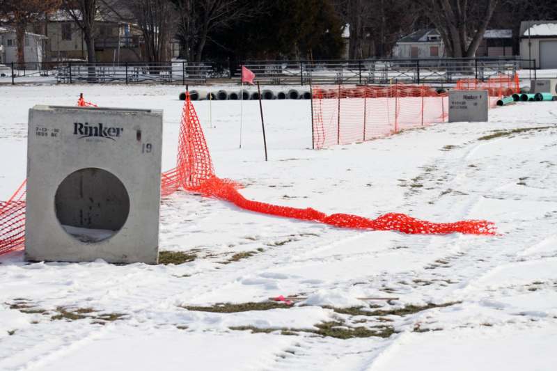 a snow covered field with orange net and a concrete box