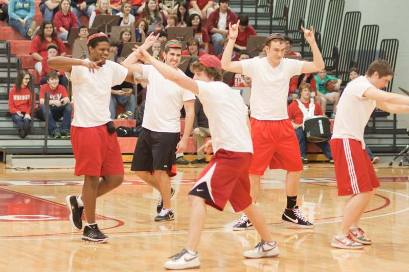 a group of men in white shirts and red shorts on a basketball court