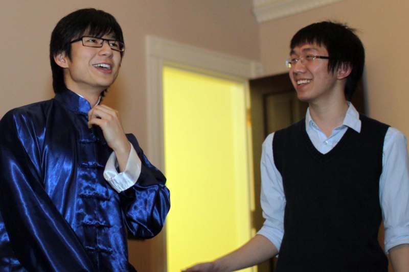 a man in a blue shirt smiling next to another man in a black vest