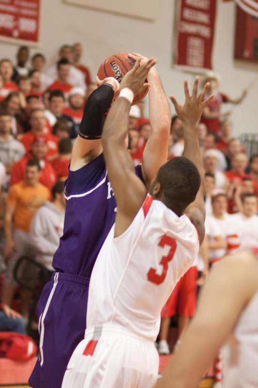 a basketball player in a purple uniform jumping to block a basketball