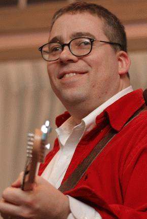 a man in red shirt and glasses holding a guitar