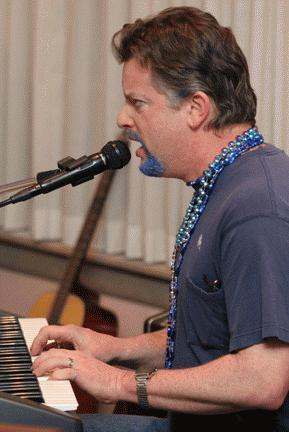 a man with blue beard and blue necklace singing into a microphone