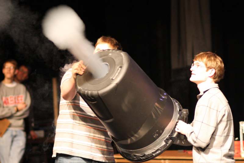 a group of boys holding a large barrel with smoke coming out of it