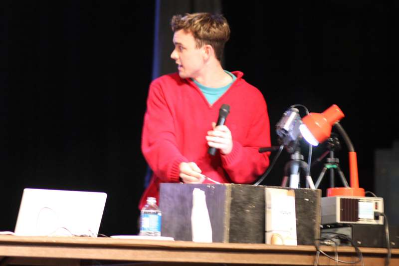 a man in a red sweater holding a microphone