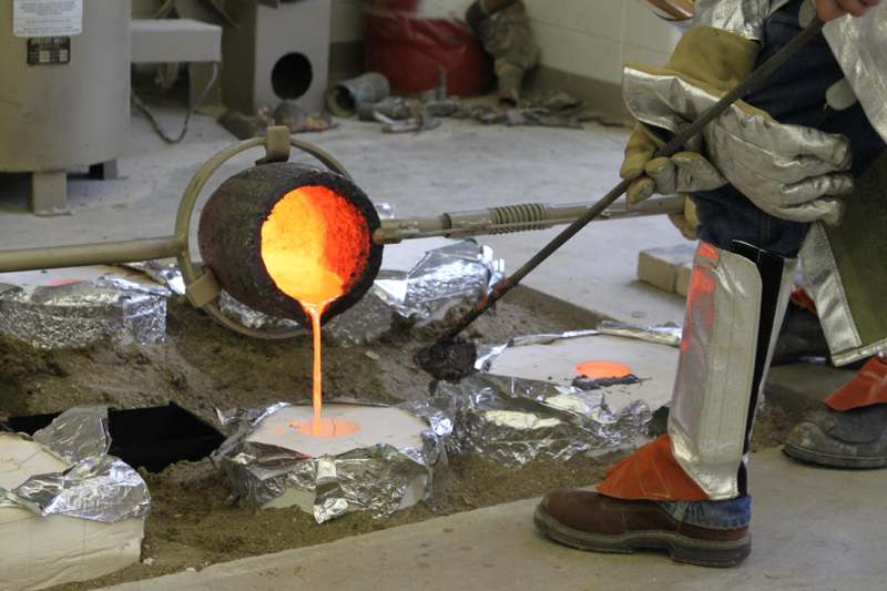 a man pouring molten metal into a pot