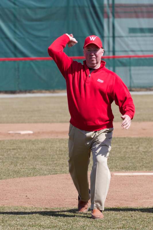 a man in a red shirt and hat on a baseball field