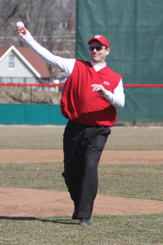 a man in a red shirt and black pants throwing a baseball