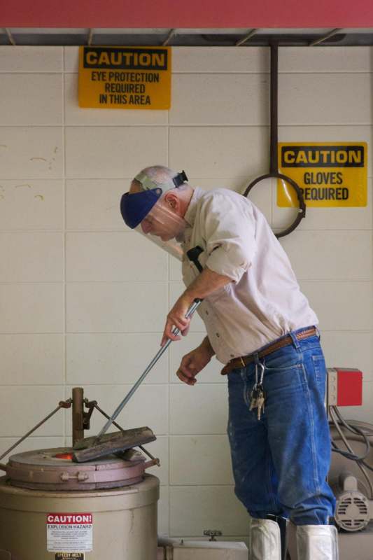 a man wearing a face shield and holding a tool