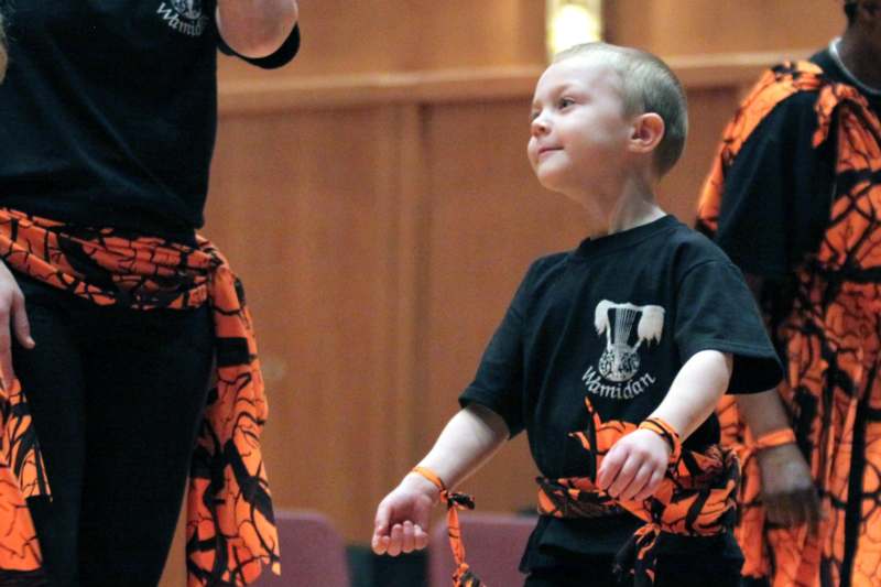 a boy wearing a black shirt tied with orange and black fabric around his neck