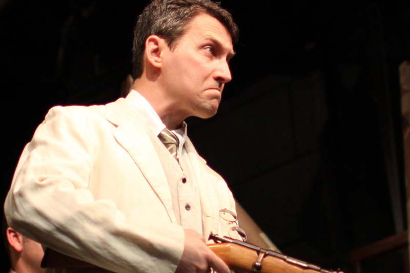 a man in a white suit holding a gun