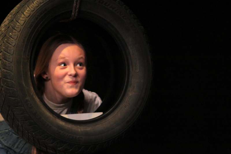a girl looking through a tire