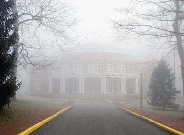 a foggy road with a building