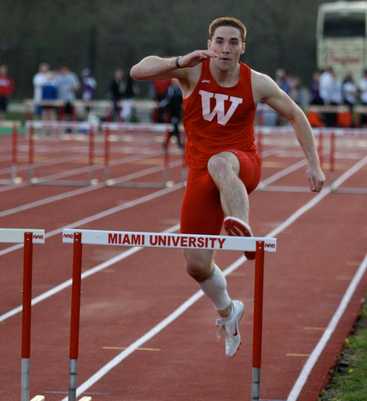 a man jumping over a hurdle on a track