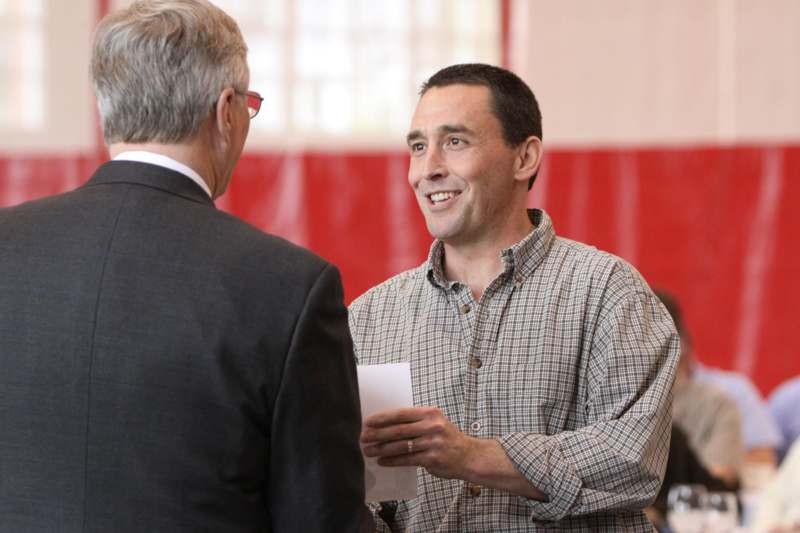 a man holding a piece of paper and talking to another man