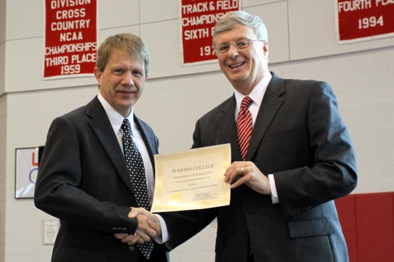 men in suits shaking hands with a certificate
