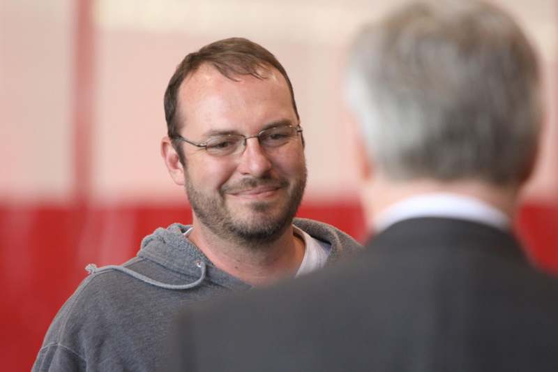 a man in glasses smiling at another man