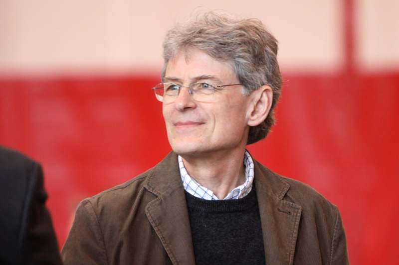 a man wearing glasses and a brown jacket