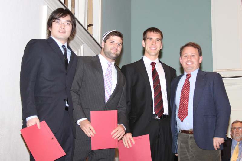 a group of men in suits holding red folders