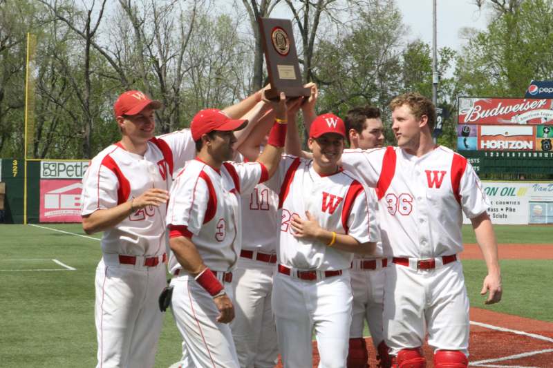 a group of baseball players holding a trophy