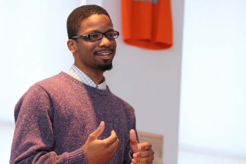 a man wearing glasses and a purple sweater