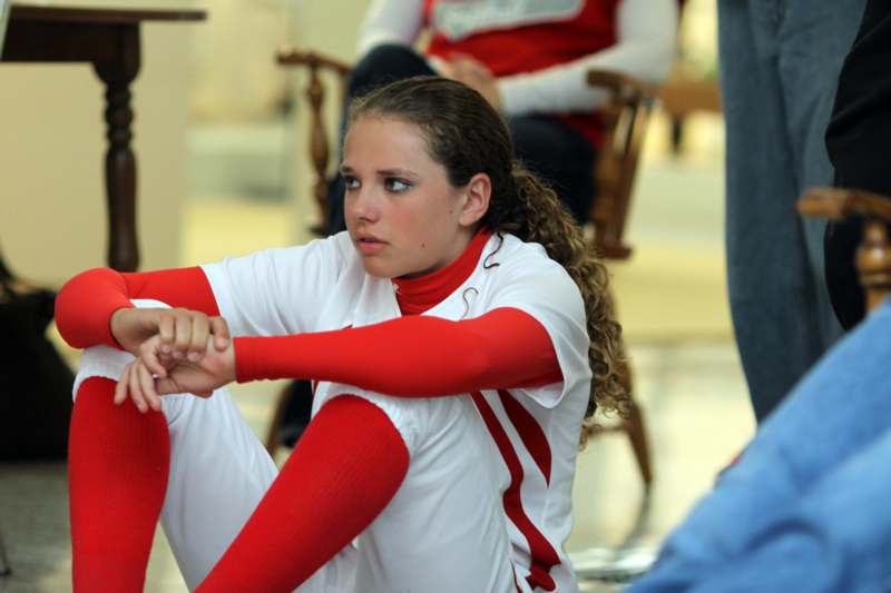 a girl in a white and red uniform sitting on the floor