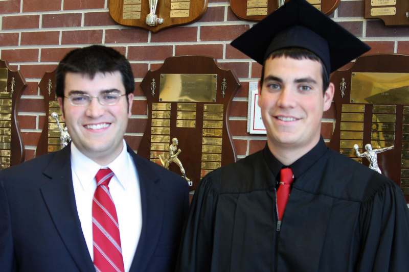 a man in a graduation cap and gown standing next to another man in a graduation cap and gown