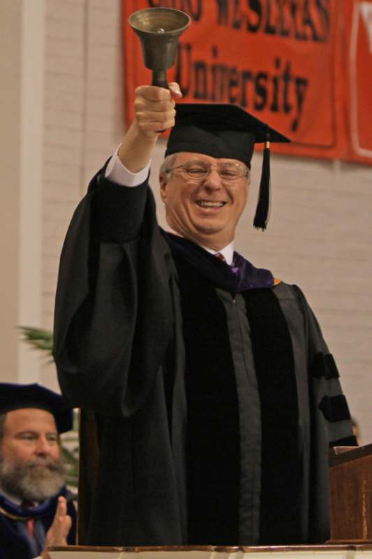 a man in a graduation gown pointing at something