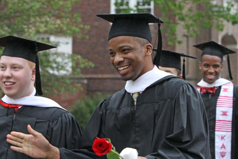 a man in graduation gowns and cap smiling