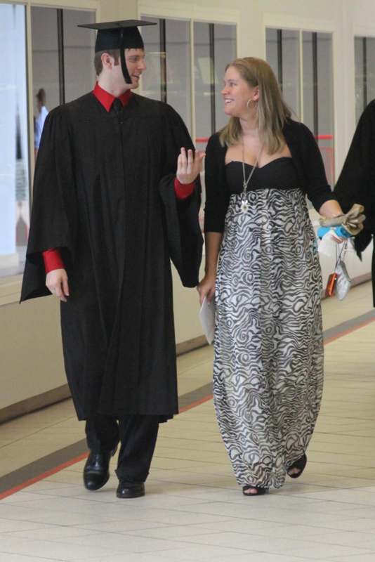 a man and woman walking in a graduation gown