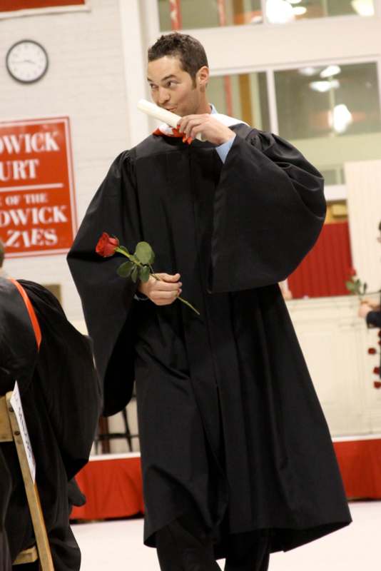 a man in a graduation gown holding a rose