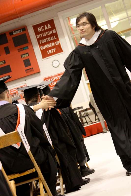 a man in a graduation gown shaking hands