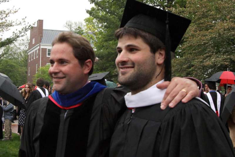 a man in graduation gowns and cap standing next to another man
