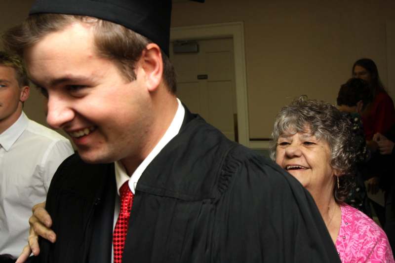 a man in a graduation gown and cap smiling