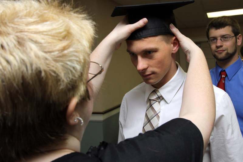 a woman putting on a graduation cap on a man