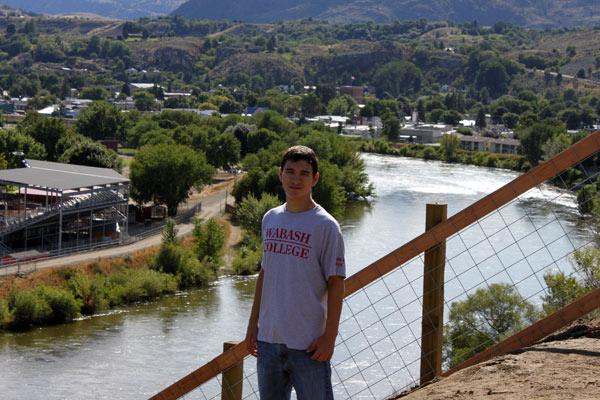 a man standing on a fence by a river