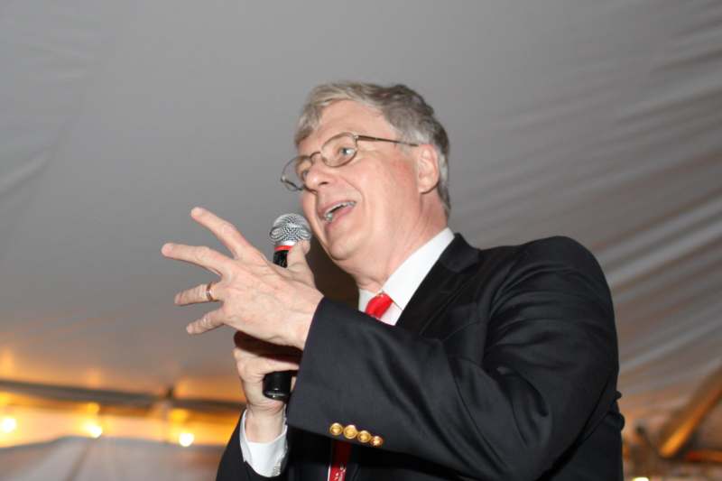 a man in a suit and tie speaking into a microphone