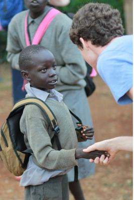 a boy with a backpack shaking hands with a person