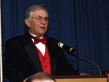 a man in a suit and bow tie speaking into a microphone