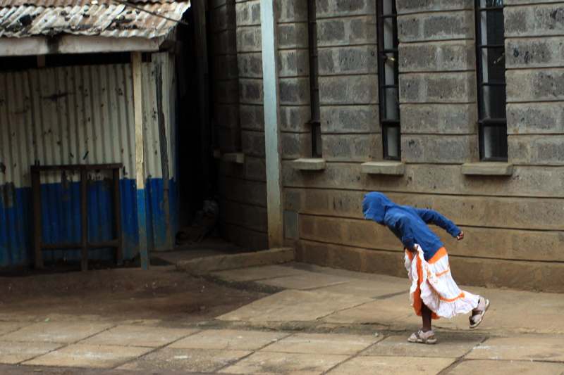 a person in a blue hoodie and white skirt bending over