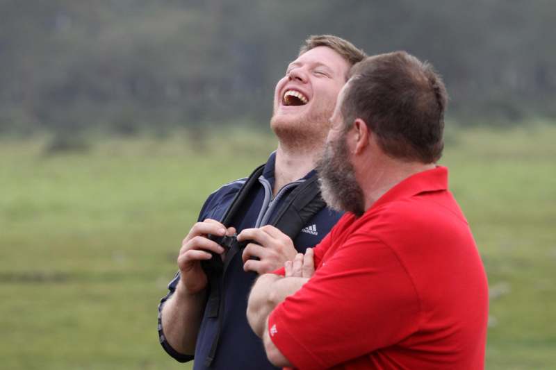two men laughing outside in a field