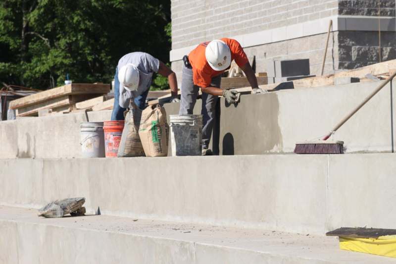 a group of men wearing hard hats and working on a concrete wall