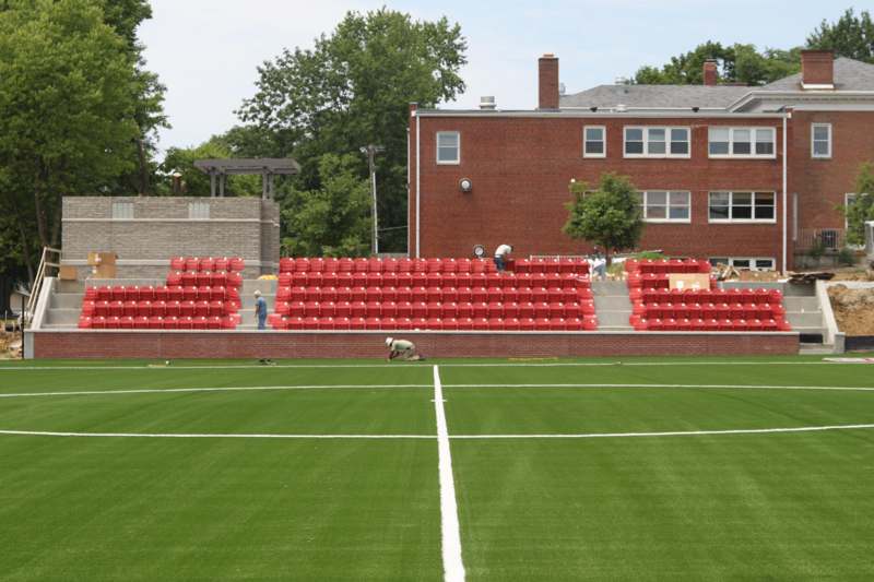 a football field with red seats and a brick building