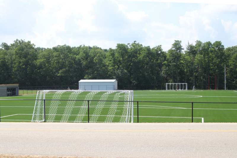 a football field with a fence and trees in the background