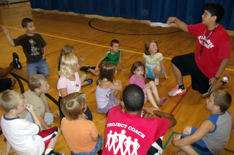a group of children sitting on a floor in a gym