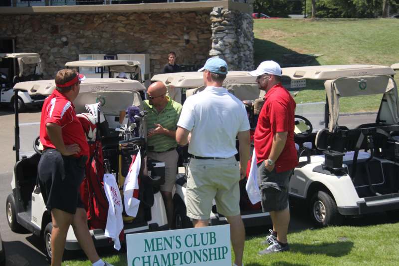 a group of men standing next to golf carts