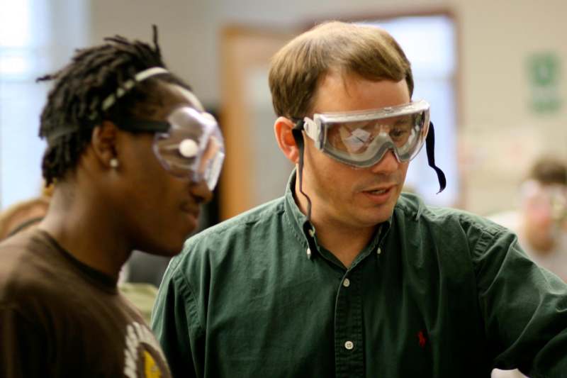 a man wearing safety goggles and looking at another man