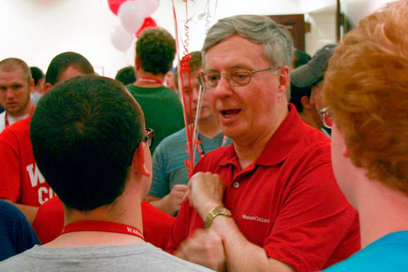 a man in a red shirt talking to a group of people