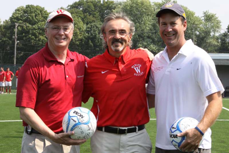 a group of men holding football balls