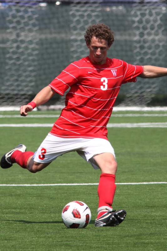 a man in a red uniform kicking a football ball
